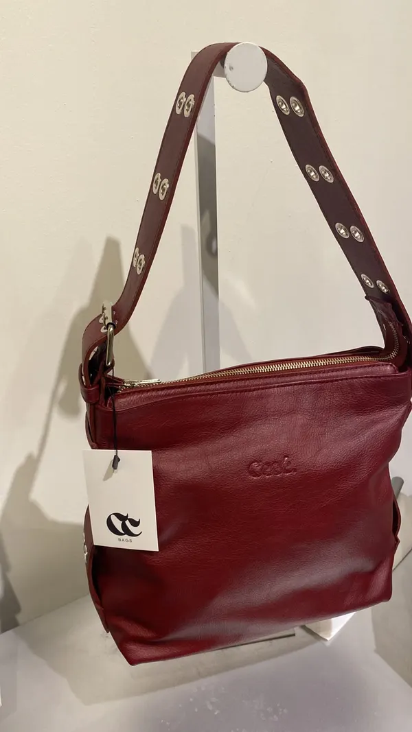 Cartera Agostina bordó en un exhibidor, con su etiqueta